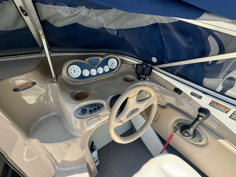 Slide: The Image of 2003 Bayliner 212 boat cockpit with steering wheel, gauges, and controls under a blue canopy. - 5