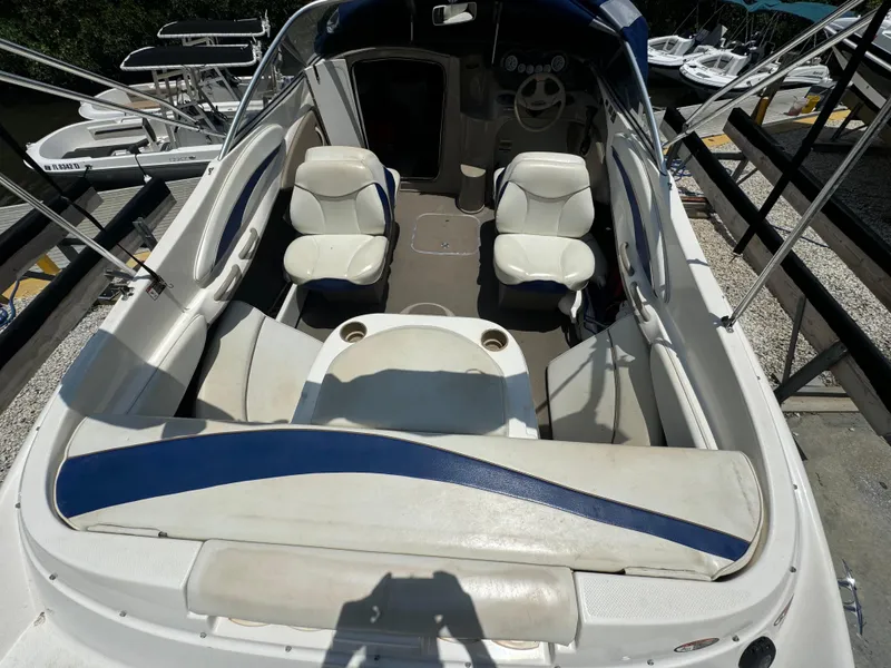 Slide: The Image of 2003 Bayliner 212 boat interior with white seating and blue accents, docked at a marina. - 9