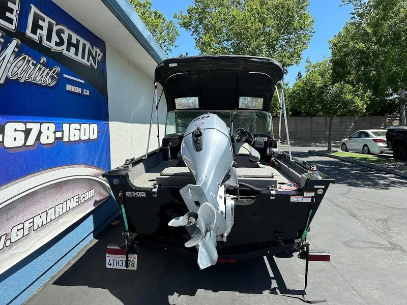 Slide: The Image of 2020 Alumacraft Classic 165 boat with outboard motor, parked outdoors near a marine shop. - 10