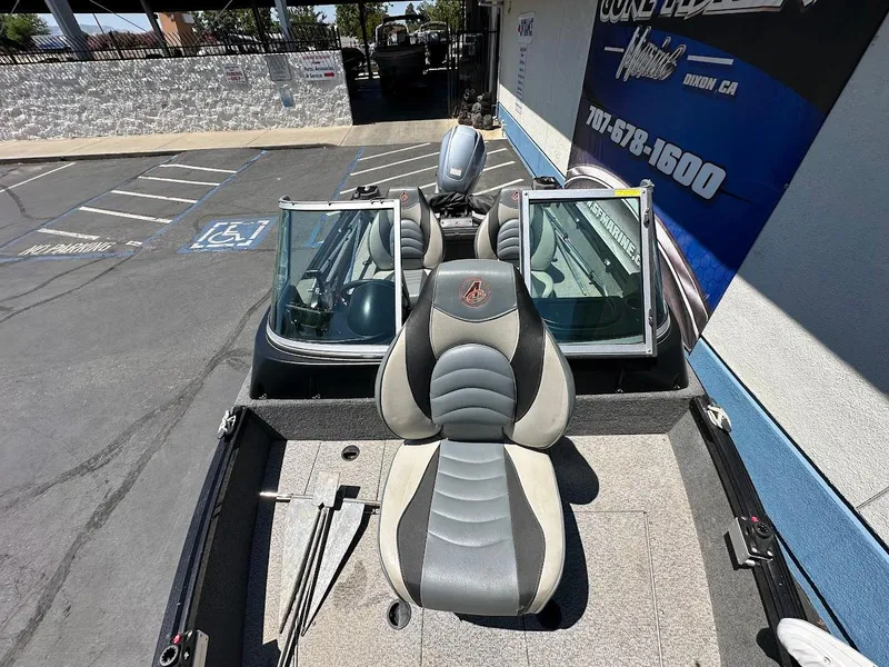 Slide: The Image of 2020 Alumacraft Classic 165 boat interior with seating and windshield, parked outdoors. - 23