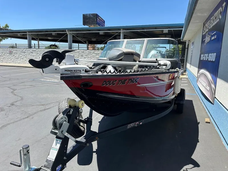 Slide: The Image of 2020 Alumacraft Classic 165 boat on trailer, parked outdoors, featuring Minn Kota trolling motor. - 5