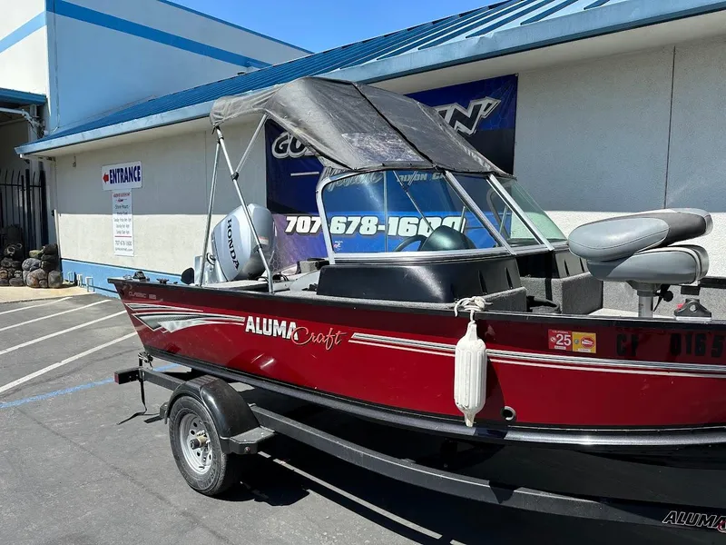 Slide: The Image of 2020 Alumacraft Classic 165 boat with canopy, parked on a trailer outside a building. - 7