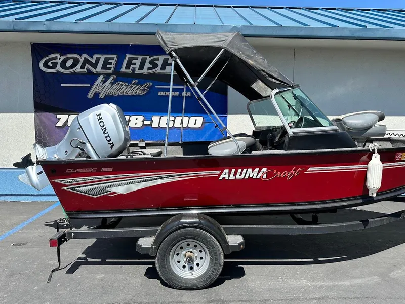 Slide: The Image of 2020 Alumacraft Classic 165 boat with Honda motor on trailer, parked outside. - 8