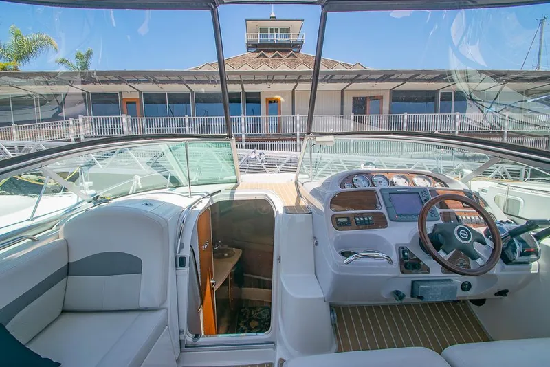 Slide: The Image of 2007 Chaparral Signature 310 boat interior with helm and seating, docked near a building. - 9