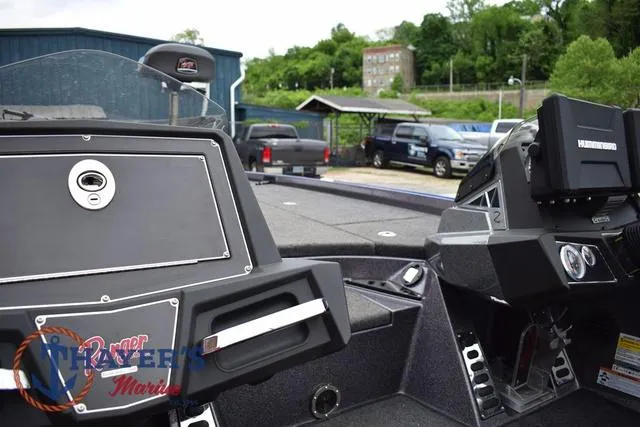 Slide: The Image of 2021 Ranger Z521L boat dashboard with electronics, parked outdoors near vehicles and greenery. - 24