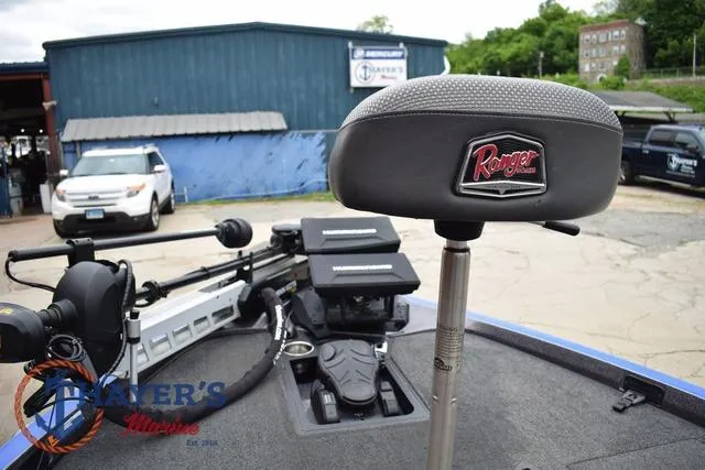 Slide: The Image of 2021 Ranger Z521L boat seat and deck, parked at a marina with vehicles in the background. - 37