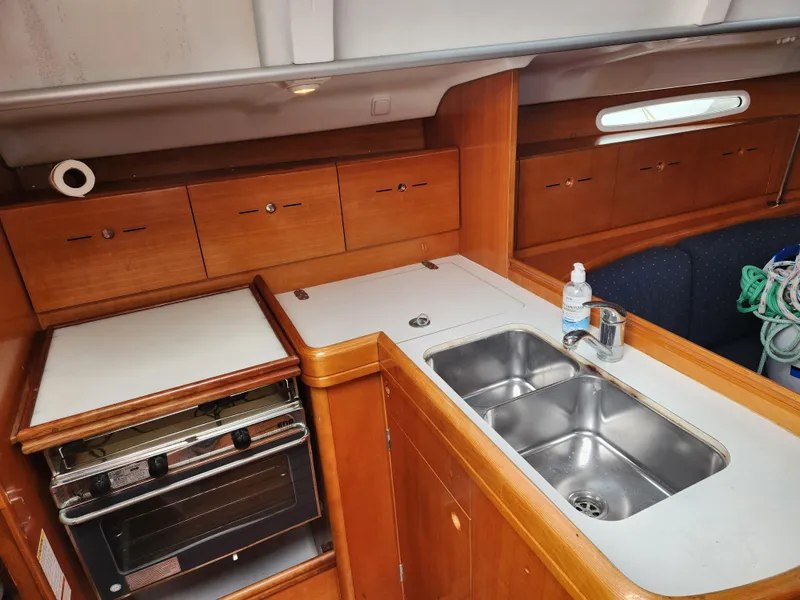 Slide: The Image of 2003 Beneteau First 40.7 yacht kitchen with wood cabinetry, dual sink, and stove. - 14