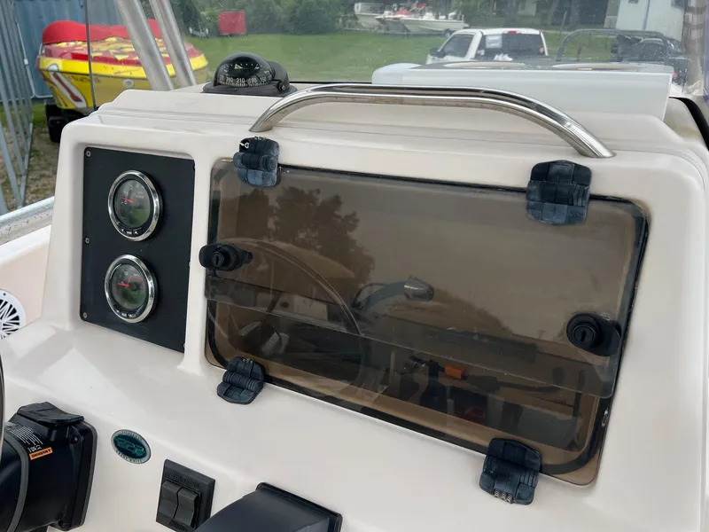 Slide: The Image of 1999 Grady-White 222 boat dashboard with gauges and storage compartment. - 13