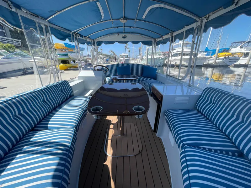 Slide: The Image of 2014 Duffy 18 Snug Harbor boat with striped seating, docked at a marina. - 13