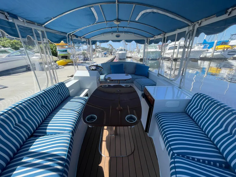 Slide: The Image of 2014 Duffy 18 Snug Harbor boat with striped seating and canopy, docked at marina. - 14