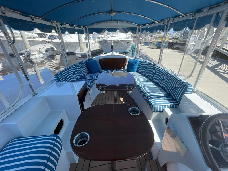 Slide: The Image of 2014 Duffy 18 Snug Harbor boat with striped seating and wooden tables, docked at marina. - 6