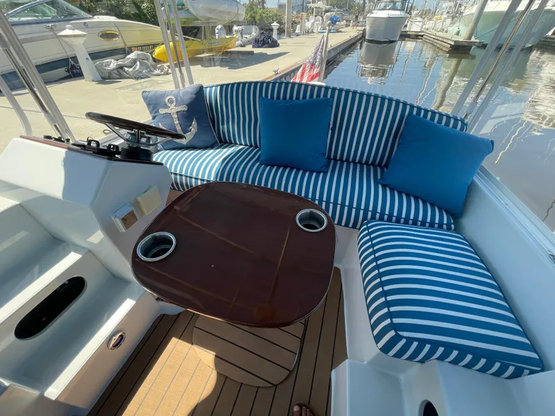 Slide: The Image of 2014 Duffy 18 Snug Harbor boat interior with striped cushions and wooden table. - 7