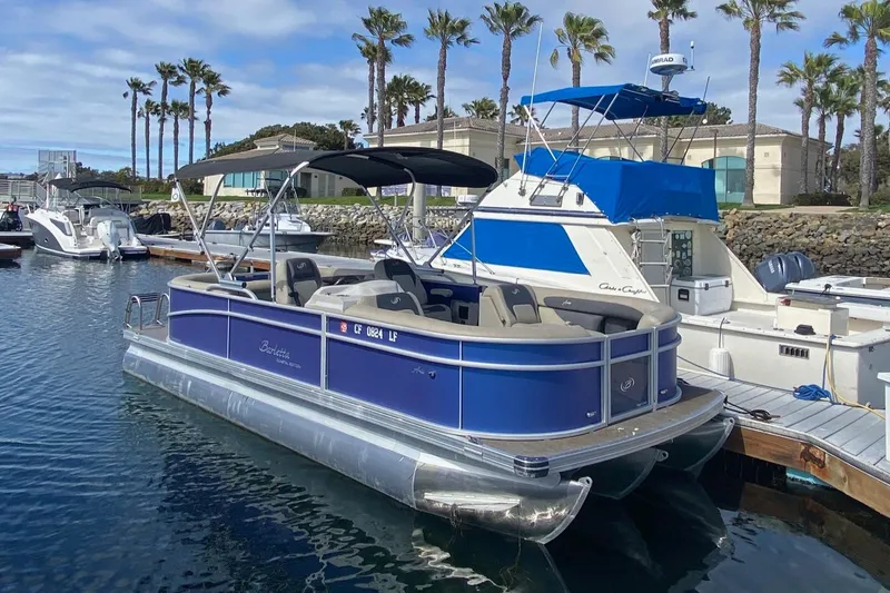 Slide: The Image of 2023 Barletta ARIA 22QC pontoon boat on trailer, blue exterior, parked outdoors. - 0