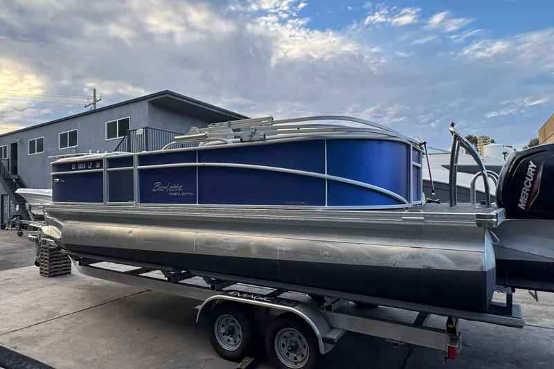 Slide: The Image of 2023 Barletta ARIA 22QC pontoon boat on trailer, blue exterior, parked outdoors. - 10