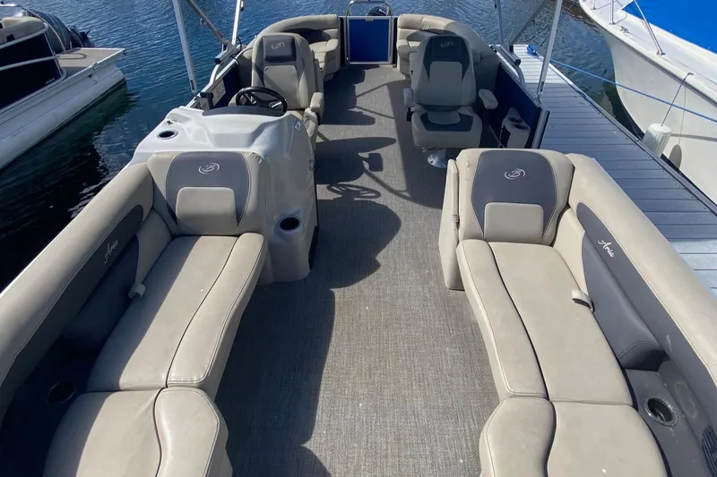 Slide: The Image of 2023 Barletta ARIA 22QC pontoon boat on trailer, surrounded by trees. - 2