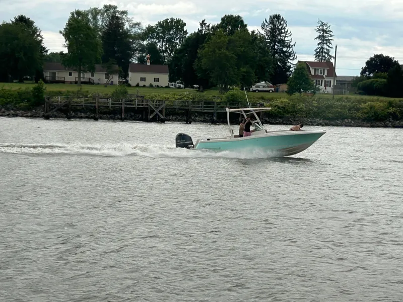 Slide: The Image of 2008 Chris-Craft Catalina 26 boat cruising on a river near a residential area. - 10