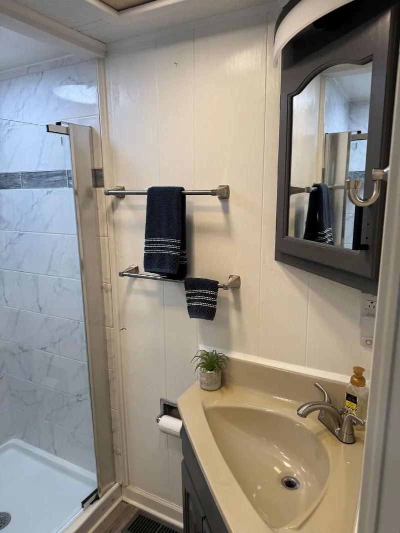 Slide: The Image of 1986 Stardust Cruisers houseboat bathroom with shower, sink, mirror, and towel rack. - 23