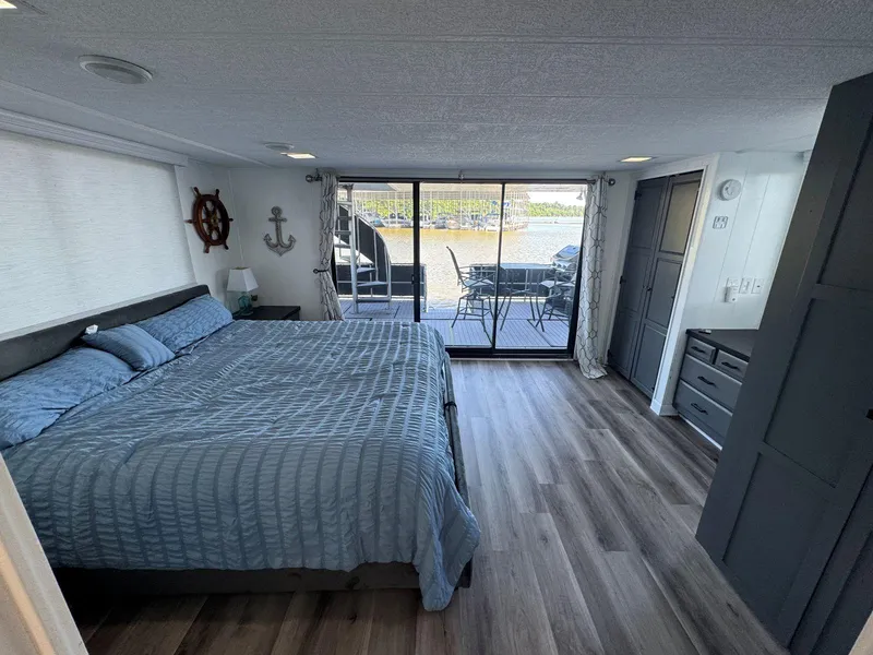 Slide: The Image of 1986 Stardust Cruisers houseboat bedroom with large bed, nautical decor, and sliding glass doors to deck. - 35