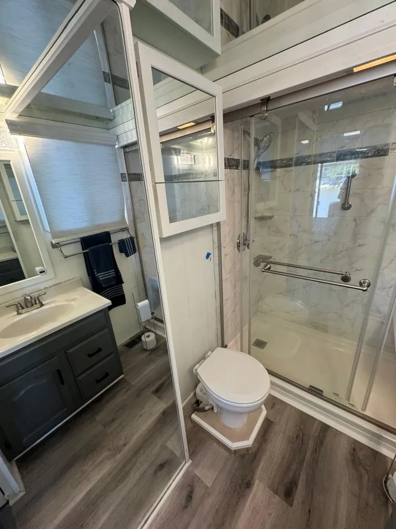 Slide: The Image of 1986 Stardust Cruisers houseboat bathroom with modern shower, vanity, and wood flooring. - 44