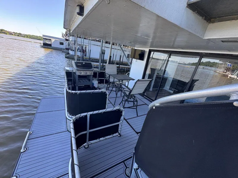 Slide: The Image of 1986 Stardust Cruisers 18 X 80 houseboat with outdoor seating on a calm lake. - 49