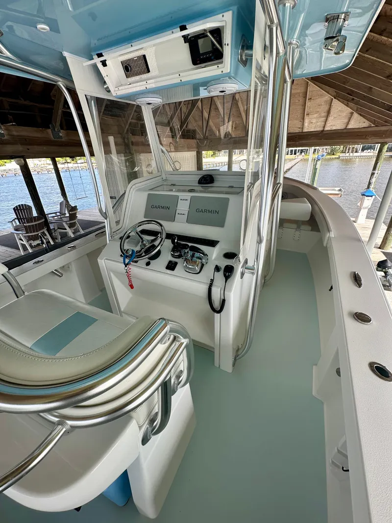 Slide: The Image of 2021 Albury Brothers 27 boat interior with modern controls and seating under a dock. - 12