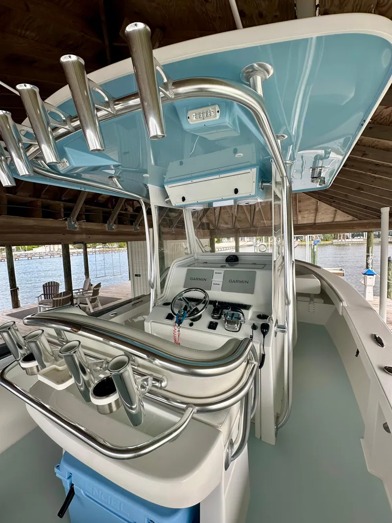 Slide: The Image of 2021 Albury Brothers 27 boat interior with helm and rod holders under a dock. - 17