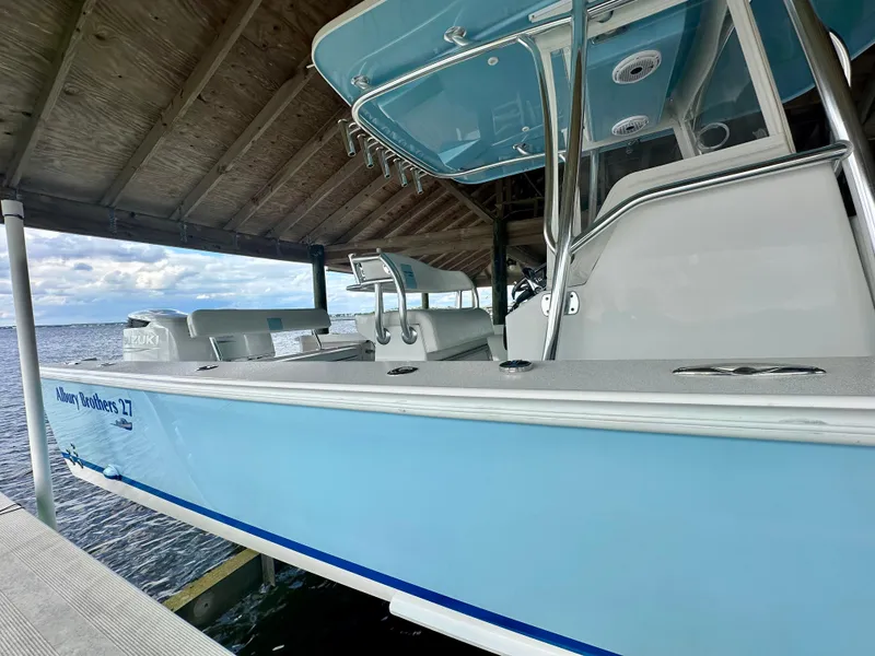Slide: The Image of 2021 Albury Brothers 27 boat docked under a wooden shelter, featuring a light blue hull. - 6
