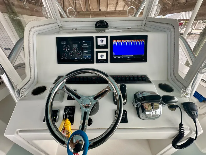 Slide: The Image of 2021 Albury Brothers 27 boat dashboard with steering wheel, dual screens, and controls. - 7