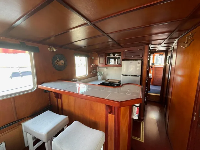 Slide: The Image of Interior of a 2010 Custom Trawler with wooden decor and a compact kitchen area. - 11