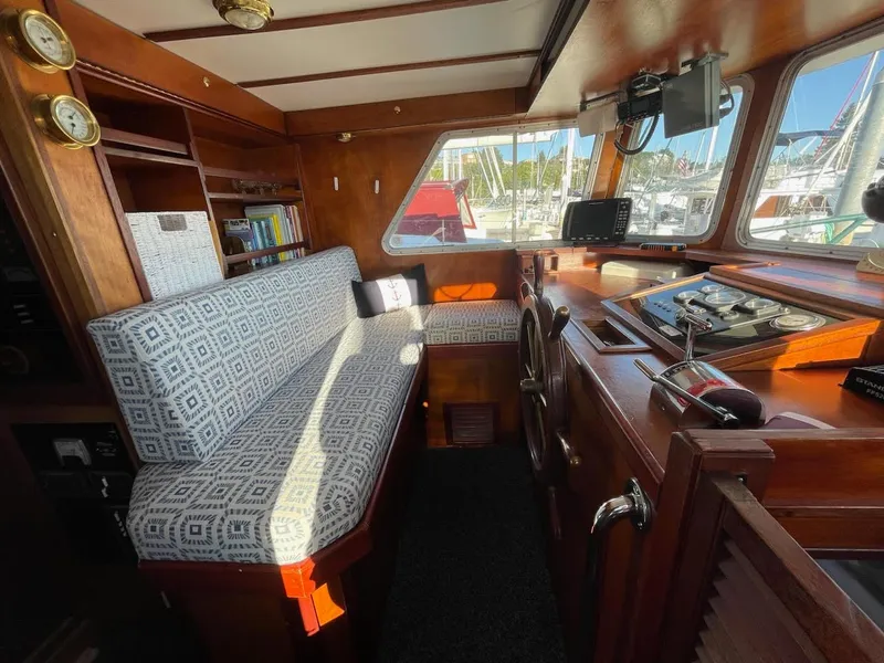 Slide: The Image of Cozy 2010 custom trawler interior with patterned seating, wooden accents, and navigational equipment. - 18