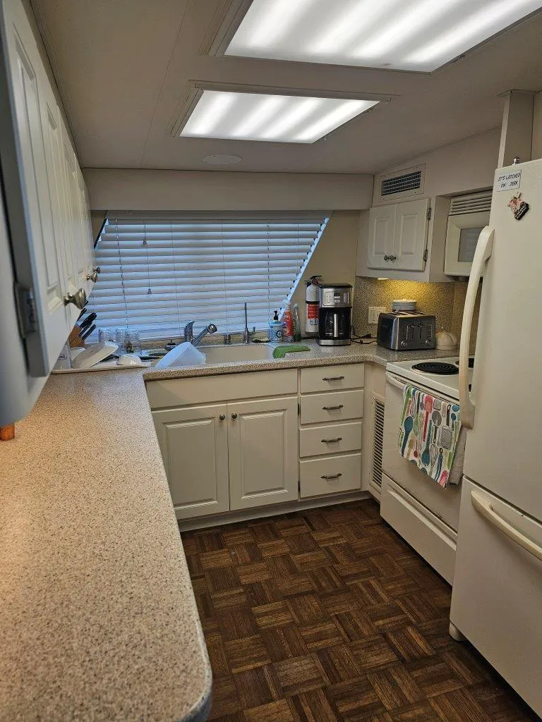 Slide: The Image of 1987 Hatteras 70 Cockpit Motor Yacht kitchen with white cabinets and wood flooring. - 11