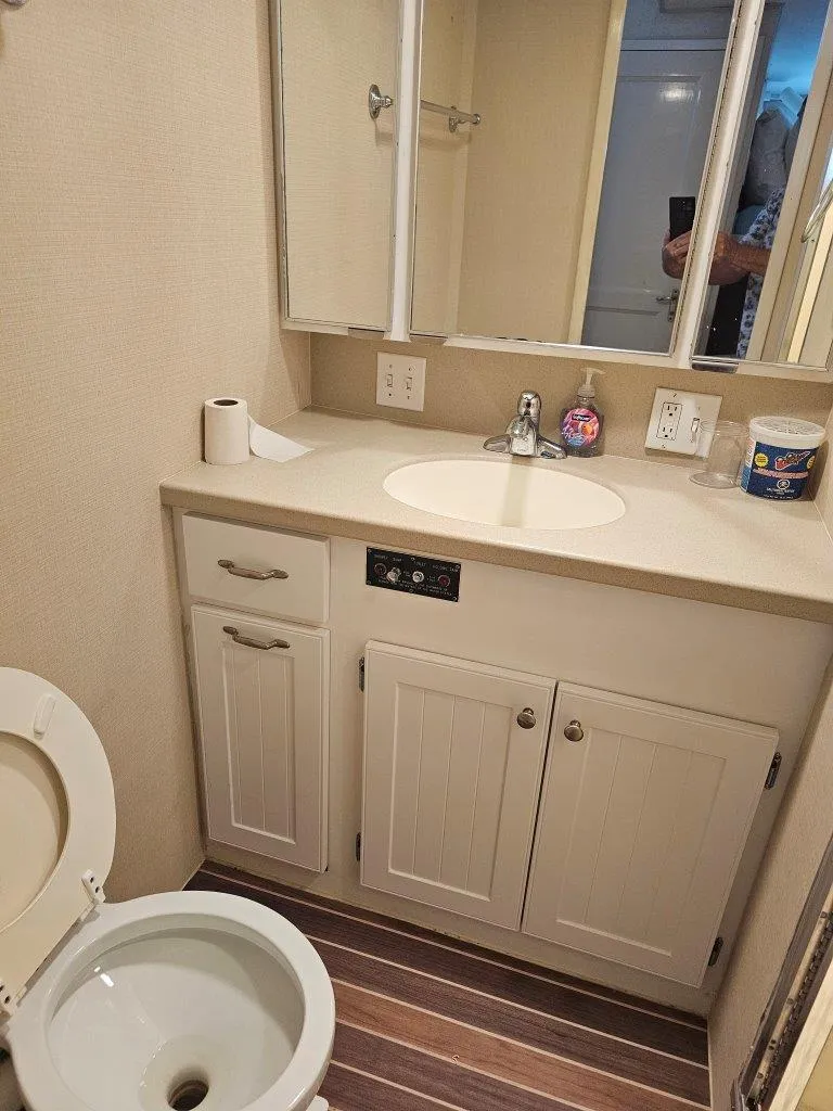 Slide: The Image of 1987 Hatteras 70 Cockpit Motor Yacht bathroom with sink, toilet, and storage cabinets. - 22