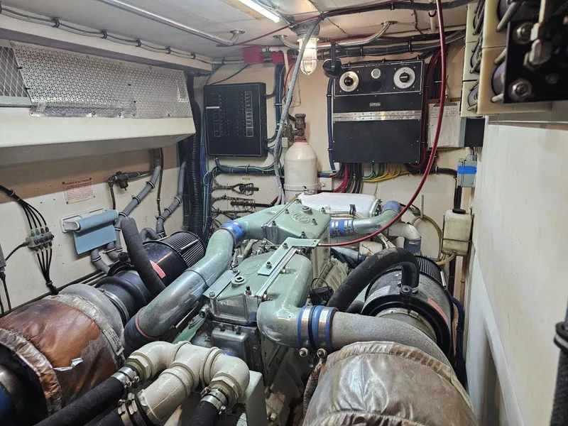 Slide: The Image of Engine room of 1987 Hatteras 70 Cockpit Motor Yacht, showcasing complex machinery and wiring. - 28