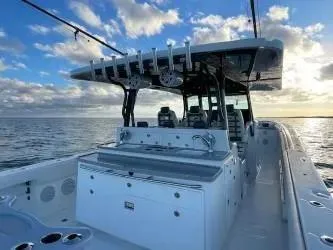 Slide: The Image of 2019 HCB 53 Sueños boat on calm ocean at sunset, featuring spacious deck and fishing equipment. - 12