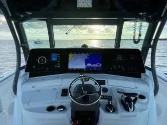 Slide: The Image of 2019 HCB 53 Sueños boat dashboard with navigation screens, steering wheel, and controls at sea. - 13