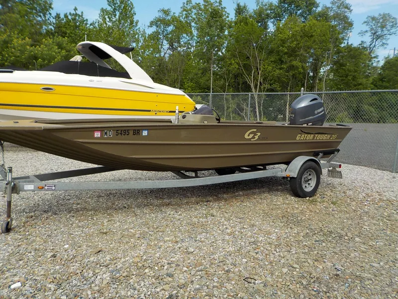 Slide: The Image of 2021 G3 20 SC boat on trailer, parked on gravel, with trees in background. - 5