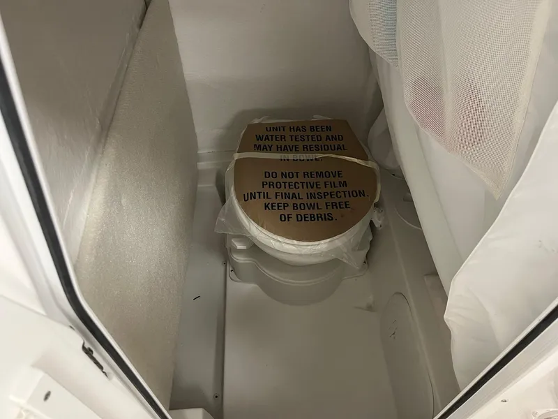 Slide: The Image of 2025 Sea Hunt Ultra 245 SE boat toilet with protective film and inspection notice. - 15