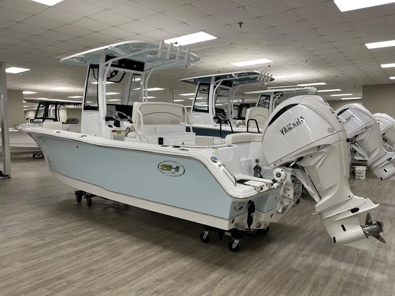Slide: The Image of 2025 Sea Hunt Ultra 245 SE boat displayed indoors with Yamaha outboard motor. - 2