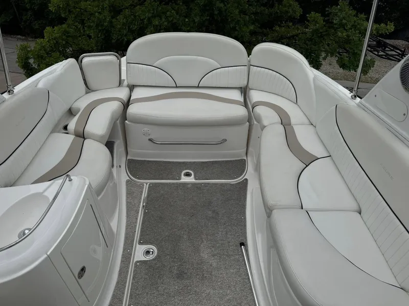 Slide: The Image of 2012 Azure AZ298 boat interior with white and beige seating, gray carpet, and lush greenery background. - 4