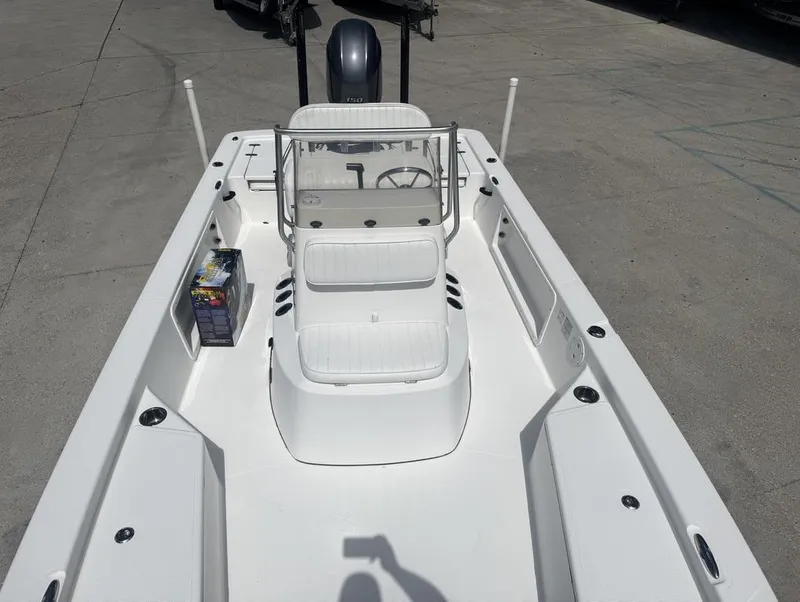 Slide: The Image of 2018 Frontier 2104 boat interior with seating and console, parked on concrete surface. - 18