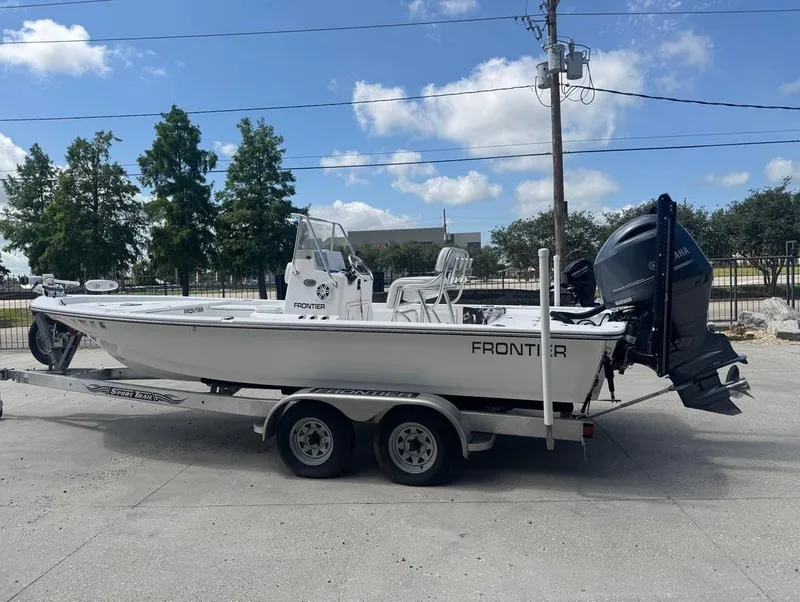 Slide: The Image of 2018 Frontier 2104 boat on trailer, parked outdoors under a clear blue sky. - 6