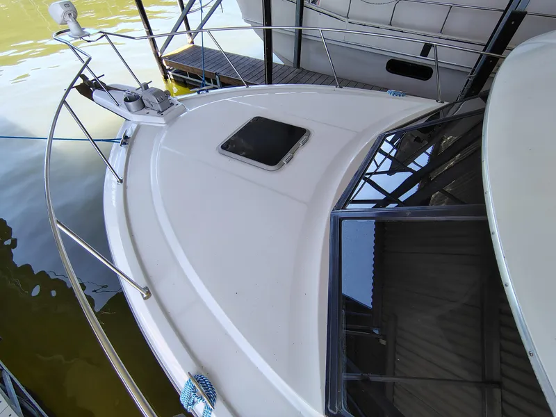 Slide: The Image of 1992 Carver Command Bridge 28 boat deck with railing and hatch, docked on calm water. - 10