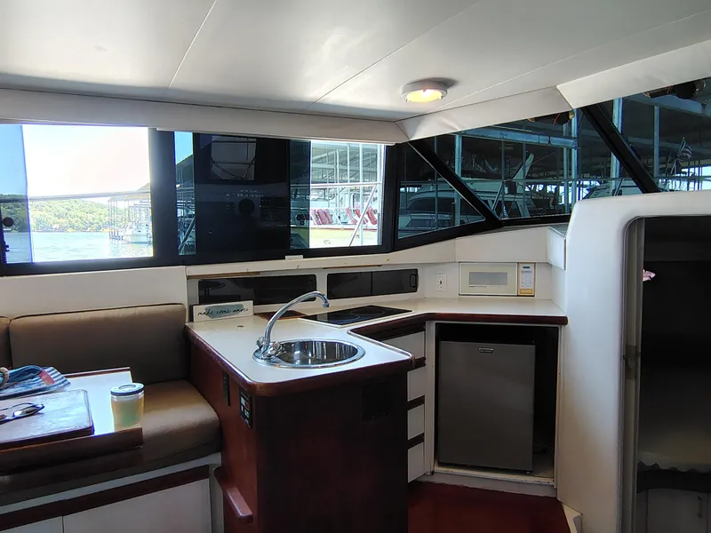 Slide: The Image of Interior of 1992 Carver Command Bridge 28, featuring kitchenette with sink, fridge, and seating area. - 22