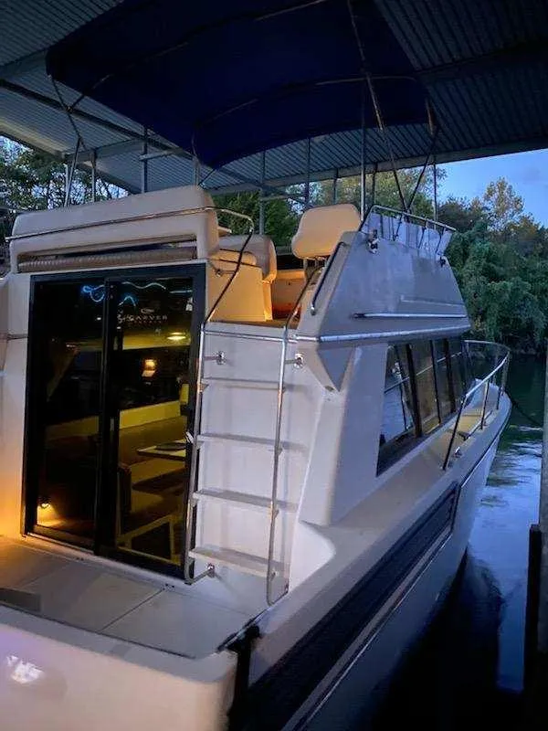 Slide: The Image of 1992 Carver Command Bridge 28 yacht with blue canopy, docked under shelter. - 28