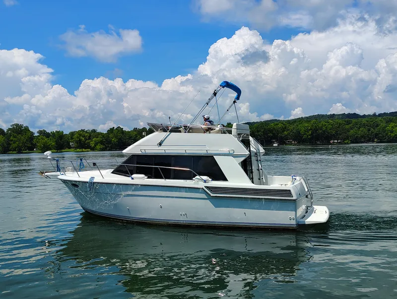 Slide: The Image of 1992 Carver Command Bridge 28 yacht cruising on a serene lake under a blue sky. - 36