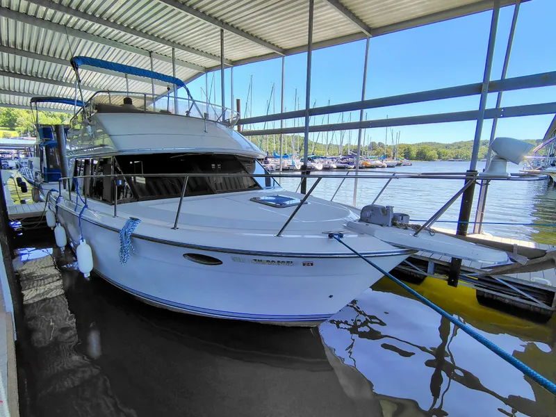 Slide: The Image of 1992 Carver Command Bridge 28 docked under a covered marina, surrounded by calm waters. - 5