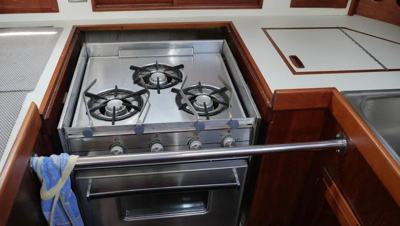 Slide: The Image of 1986 Ericson 35 MKIII yacht kitchen with stainless steel stove and wooden cabinetry. - 21