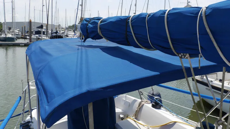 Slide: The Image of 1986 Ericson 35 MKIII sailboat with blue canvas cover docked at marina. - 6