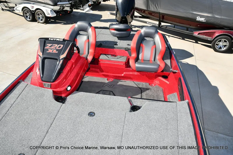 Slide: The Image of 2025 Nitro Z20 XL Pro boat interior with red and gray seating, parked on concrete. - 10