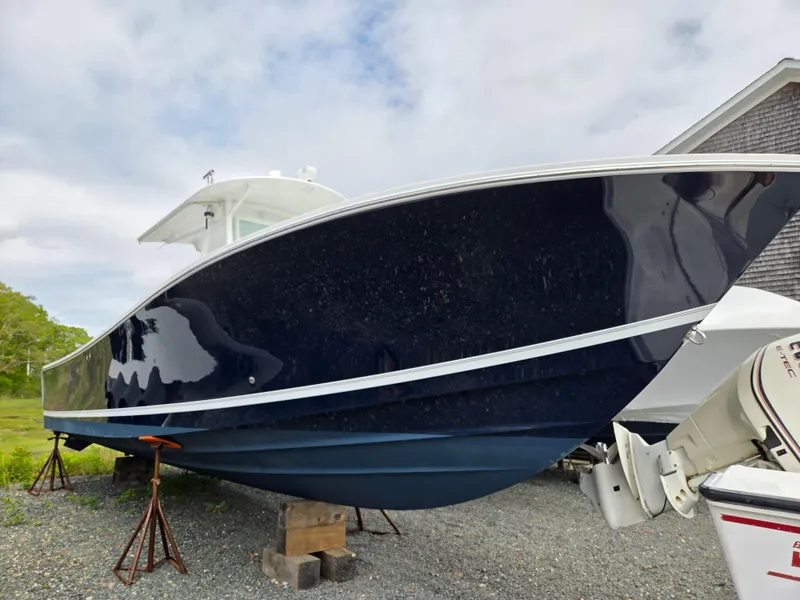 Slide: The Image of 2005 Regulator 32 Forward Seating boat on stands, blue hull, outdoor setting. - 2